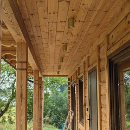 Global Elektro Grzegorz Duda, Łukasz Gołdyn Spółka Cywilna - Drewniany taras z zamontowanym oświetleniem punktowym w suficie. Widoczna drabina sugeruje niedawny montaż. Naturalne światło dzienne.