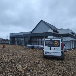 Global Elektro Grzegorz Duda, Łukasz Gołdyn Spółka Cywilna - Nowoczesny dom w trakcie budowy z rusztowaniami, na pierwszym planie biały bus firmy elektrycznej Global Elektro z widocznym logo i numerem rejestracyjnym KWI 37983.