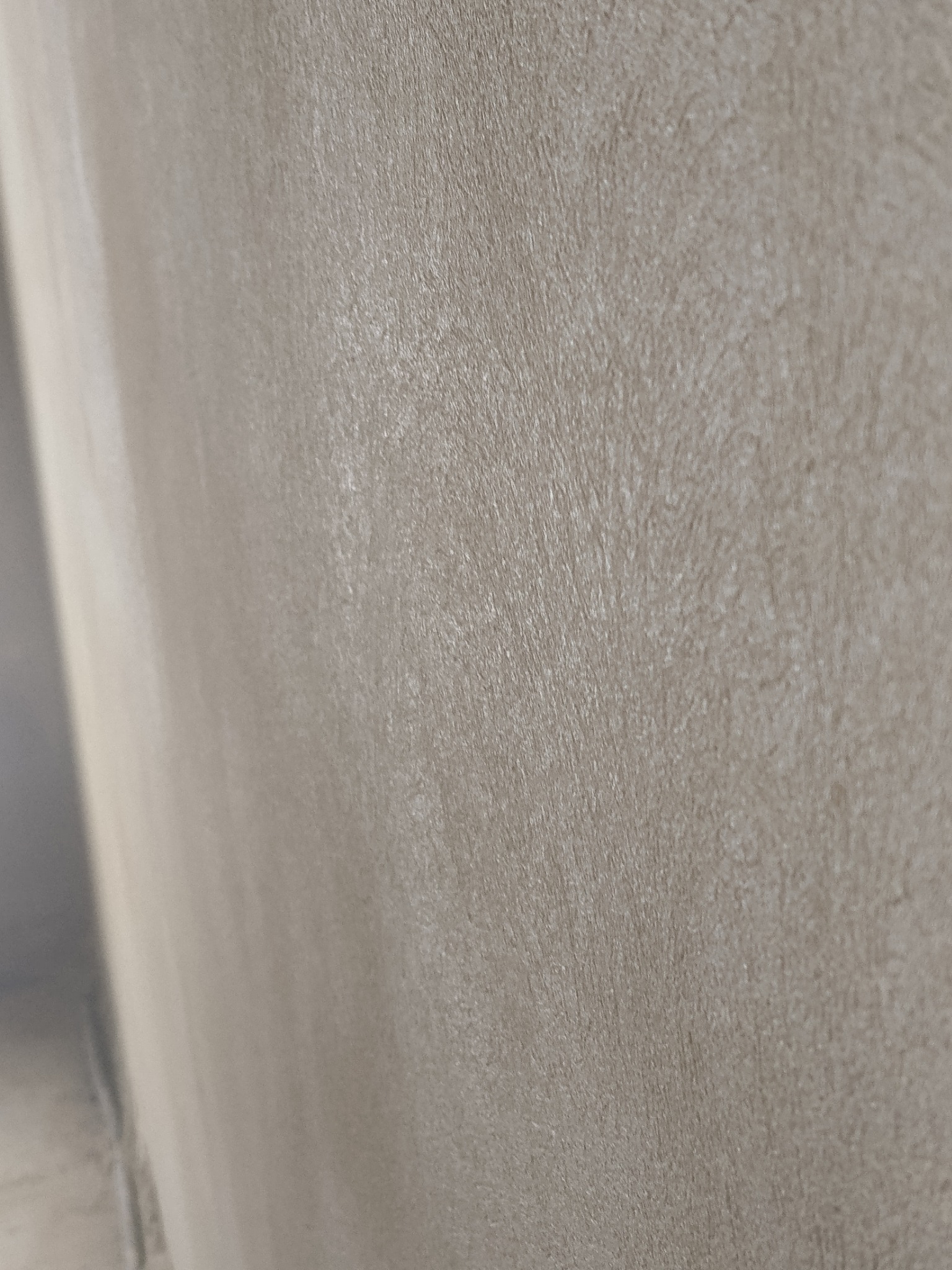 Gładka, szara ściana po nałożeniu tynku maszynowego, widoczna z bliska pod kątem, ukazująca fakturę i równomierne wykończenie powierzchni.