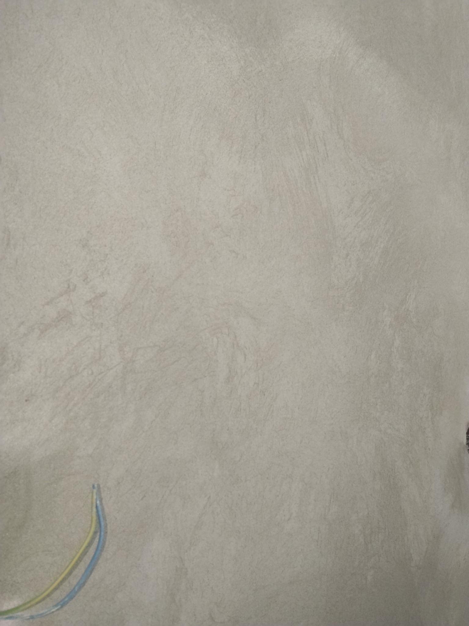 Gładka, szara ściana po nałożeniu tynku z widocznymi śladami narzędzi i wystającymi przewodami elektrycznymi w lewym dolnym rogu.