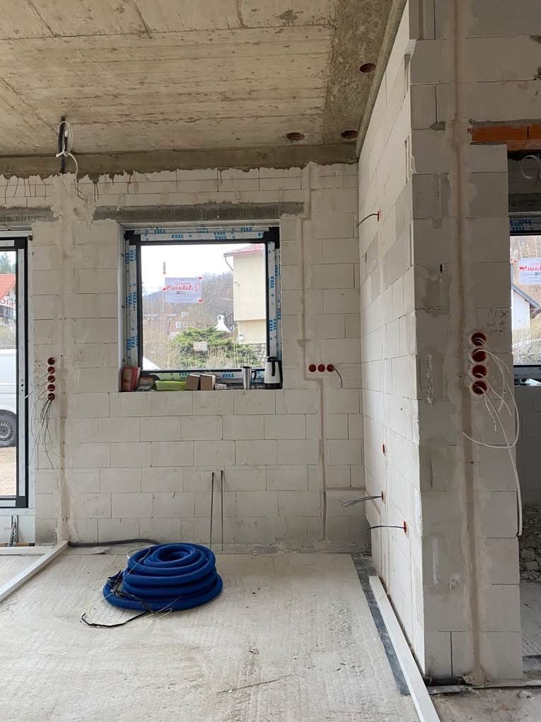 Stan surowy wnętrza w Jeleniej Górze z widoczną instalacją elektryczną w ścianach z betonu komórkowego i niebieską rurą karbowaną na podłodze.