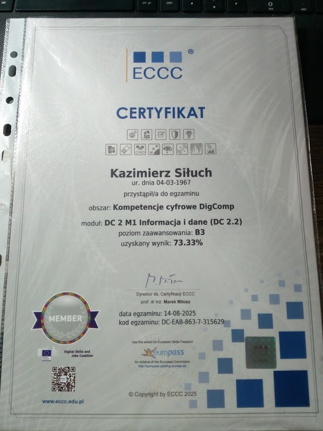 Certyfikat ECCC Kazimierza Siłucha z 2025 r. potwierdzający kompetencje cyfrowe DigComp na poziomie B3 z wynikiem 73.33%. Dokument w folii ochronnej, leży na klawiaturze.