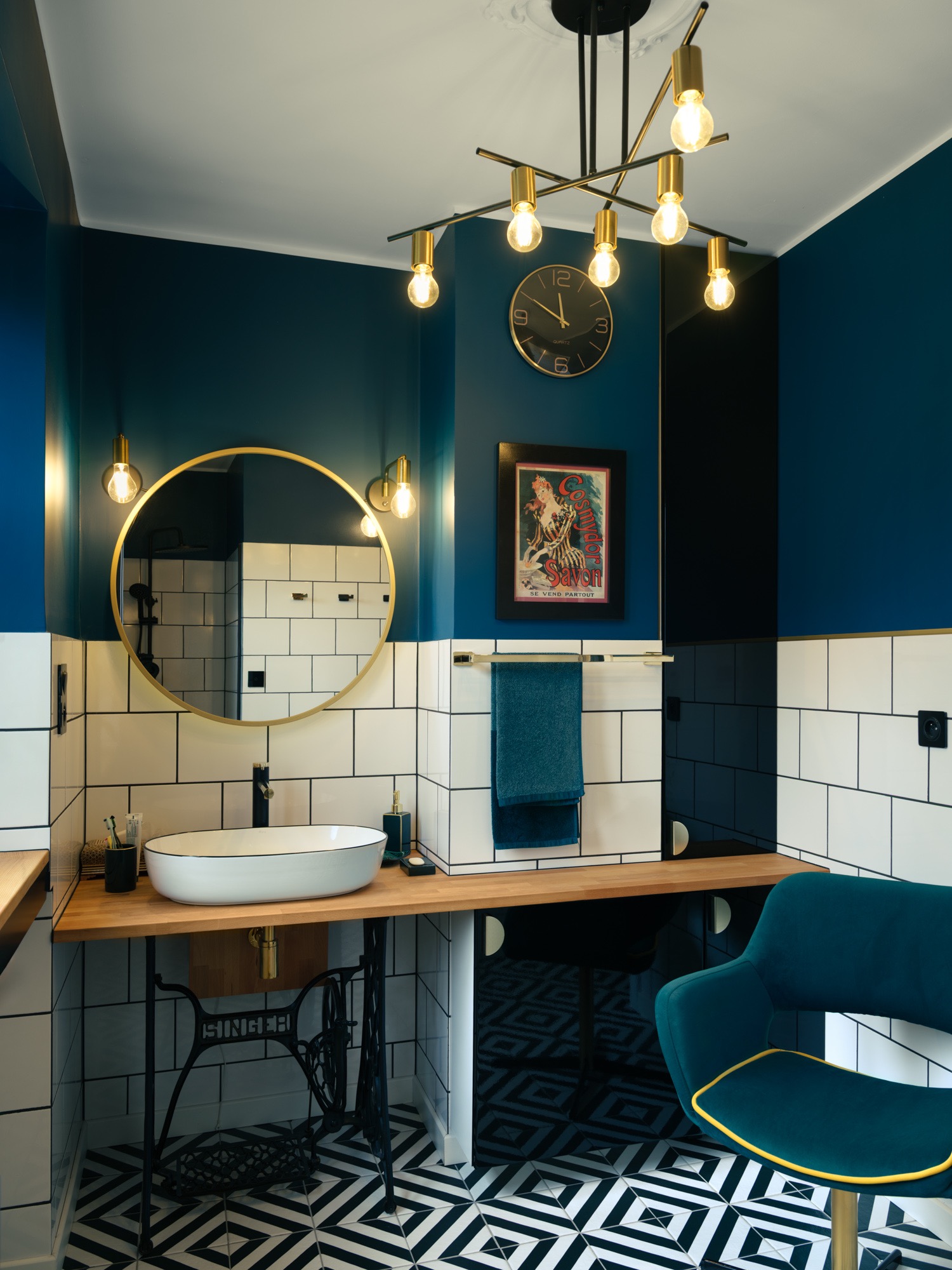 Niebiesko-biała łazienka z okrągłym lustrem, umywalką na blacie z maszyną do szycia Singer i wzorzystą podłogą. Nowoczesny design z elementami retro.
