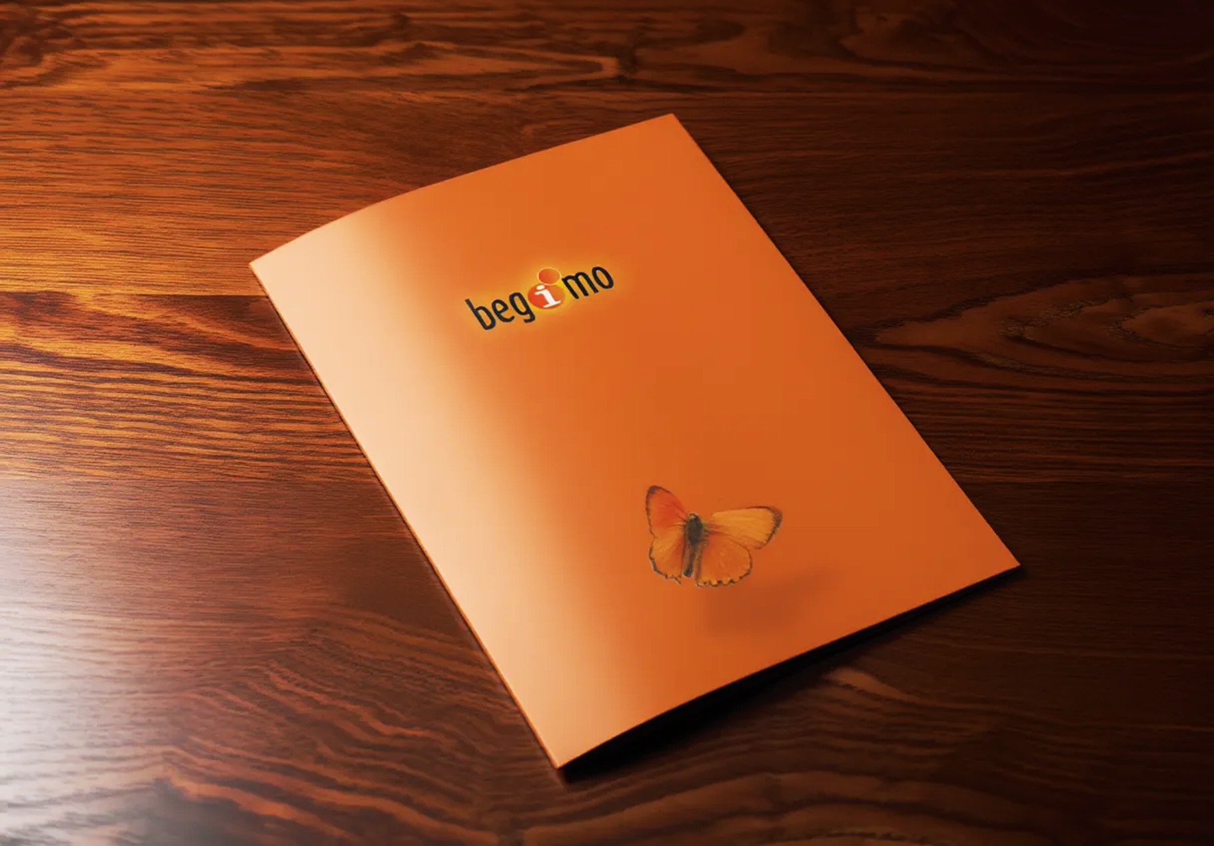 Pomarańczowa teczka z logo i motylem na drewnianym stole, prezentująca identyfikację wizualną firmy.