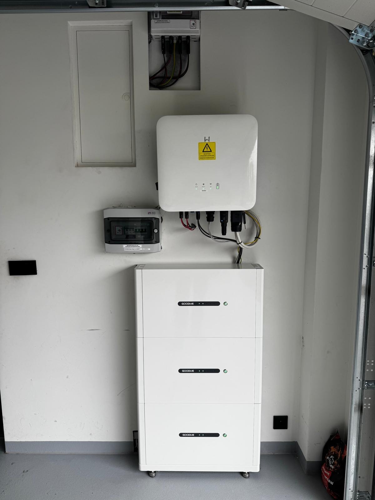 Biały magazyn energii GoodWe, falownik i licznik na ścianie w garażu. Kompletna instalacja fotowoltaiczna wewnątrz budynku.