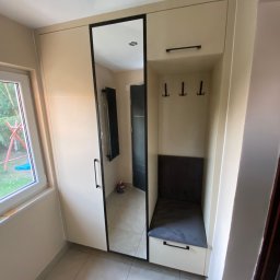 Meblosztos - Beżowa szafa wnękowa z lustrem w czarnej ramie i siedziskiem z szufladą, uzupełniona o wieszaki. Widok na wnętrze przez lustro.