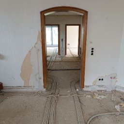 Serhii Rakomin - Rozprowadzone kable elektryczne w peszlach na podłodze w trakcie remontu mieszkania. Widoczne ślady po kuciu w ścianach i otwory na gniazdka.