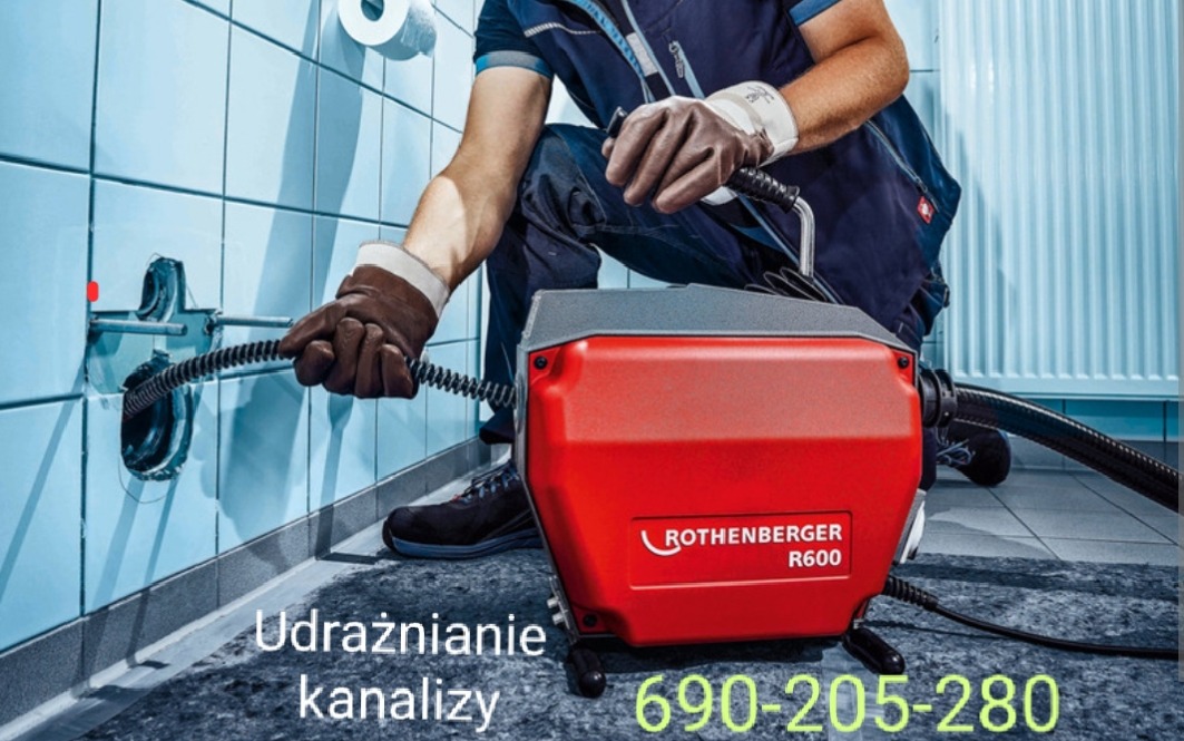 Hydraulik w trakcie udrażniania rury kanalizacyjnej za pomocą specjalistycznego urządzenia Rothenberger R600 w pomieszczeniu z niebieskimi płytkami.