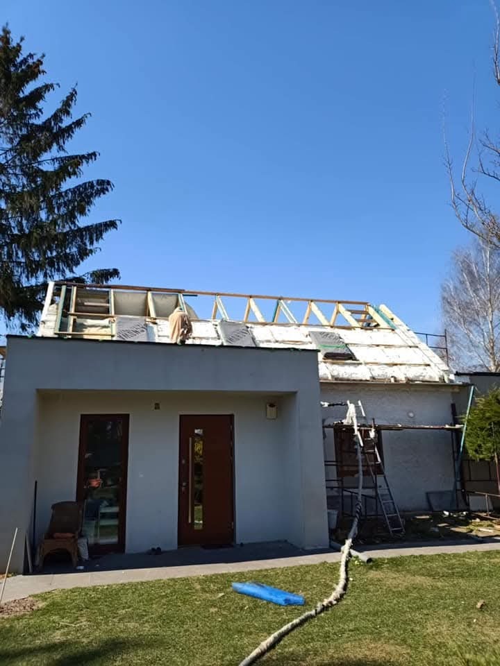 Prace związane z ociepleniem dachu domu jednorodzinnego w Strażowie. Widoczne elementy konstrukcji i izolacji. Prace w toku, widok z zewnątrz, słoneczny dzień.