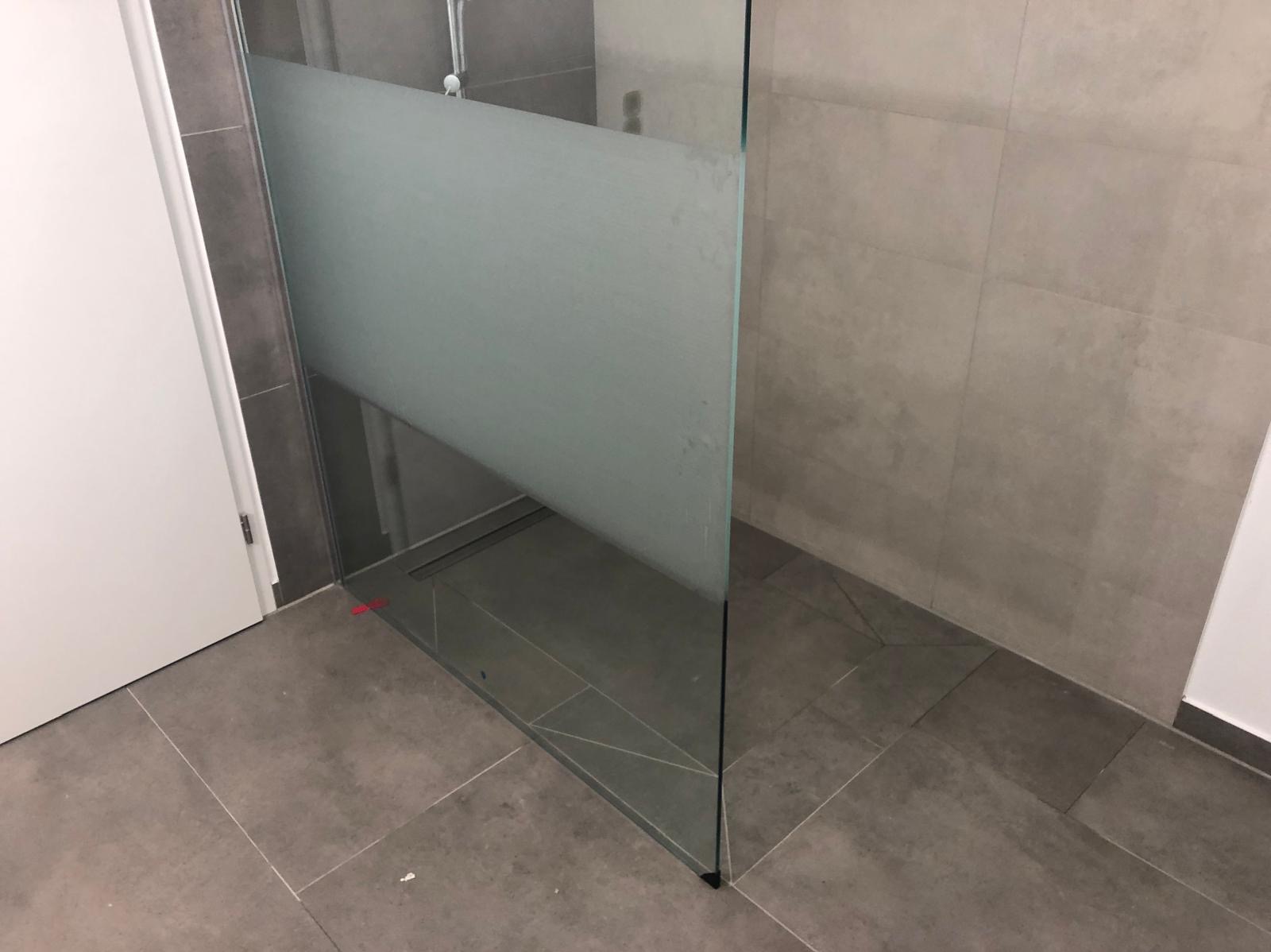 Nowoczesna kabina prysznicowa z matową szybą i odpływem liniowym, wykończona szarą płytką. Minimalistyczny design łazienki po remoncie.