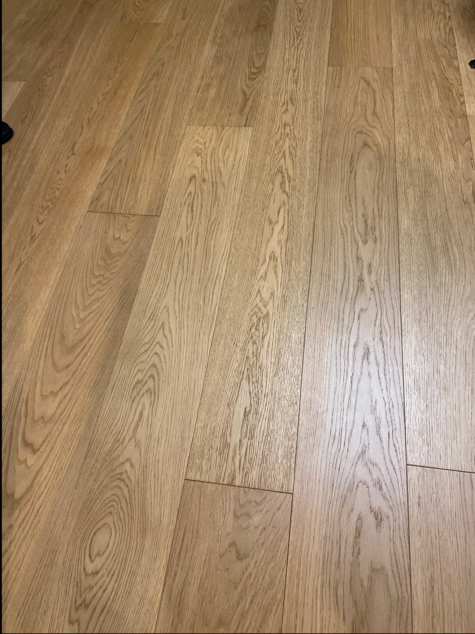 Ułożona podłoga z paneli drewnianych o jasnym odcieniu, widoczne naturalne słoje drewna. Perspektywa z niskiego kąta podkreśla fakturę i wzór podłogi.