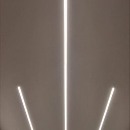 GRENOVA Marcin Gregorczuk - Nowoczesne oświetlenie sufitowe z trzema liniowymi lampami LED, tworzącymi geometryczny wzór. Minimalistyczny design, ciepłe światło, widoczny fragment ściany i sufitu.