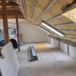 Patryk Puchalski - Montaż izolacji i metalowej konstrukcji pod okładziny w poddaszu. Widoczne profile, wełna mineralna i częściowo zamontowane oświetlenie.