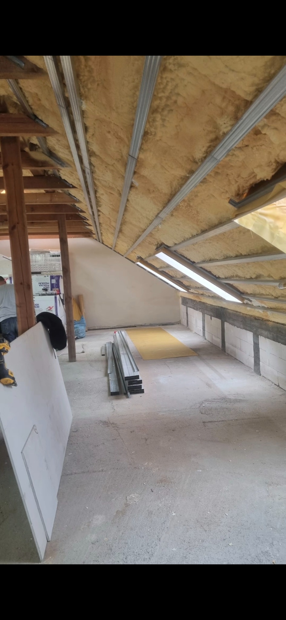 Montaż izolacji i metalowej konstrukcji pod okładziny w poddaszu. Widoczne profile, wełna mineralna i częściowo zamontowane oświetlenie.