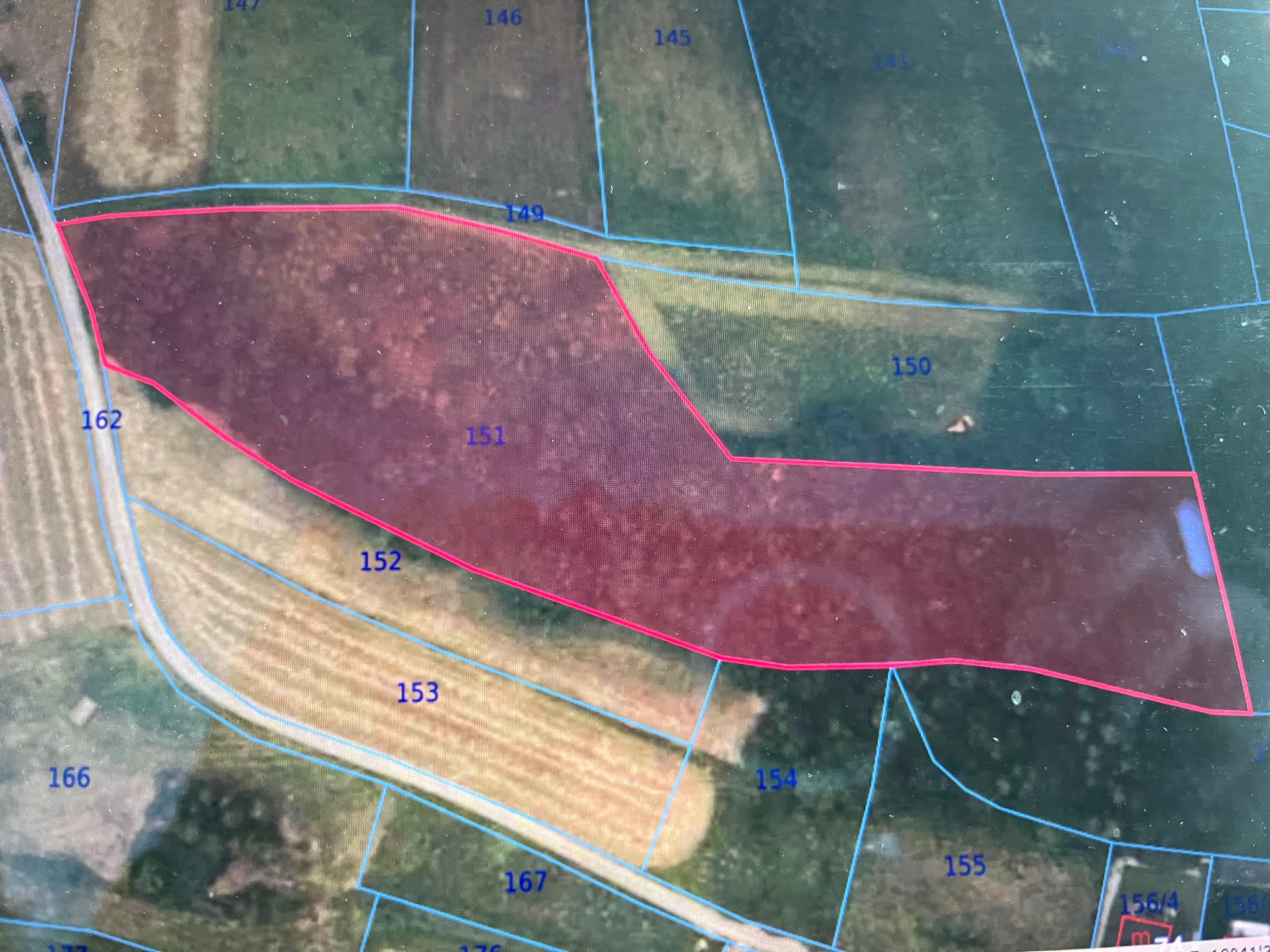 Mapa działki z numerami ewidencyjnymi, obrysowana czerwoną linią, widok z lotu ptaka. Prezentacja granic działki na tle krajobrazu.