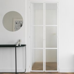 Remton - Nowoczesne wnętrze: parkiet w jodełkę, białe ściany, przeszklone drzwi z białymi ramami, okrągłe lustro i czarna konsola z figurką psa.