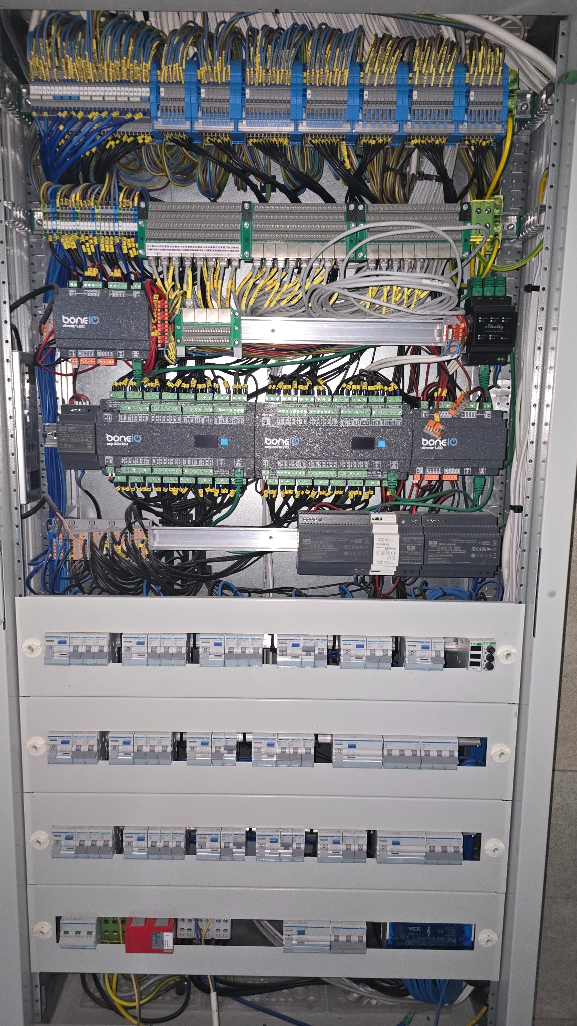 Rozdzielnica elektryczna z licznymi przewodami, modułami sterującymi i zabezpieczeniami. Widoczne szczegóły połączeń i komponentów wewnątrz szafy sterowniczej.