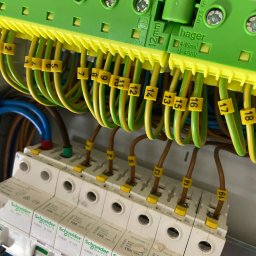 POLTHOM Paweł Kietla - Szczegółowe ujęcie rozdzielnicy elektrycznej z numerowanymi przewodami, bezpiecznikami Schneider Electric i elementami Hager, ukazujące profesjonalny montaż.