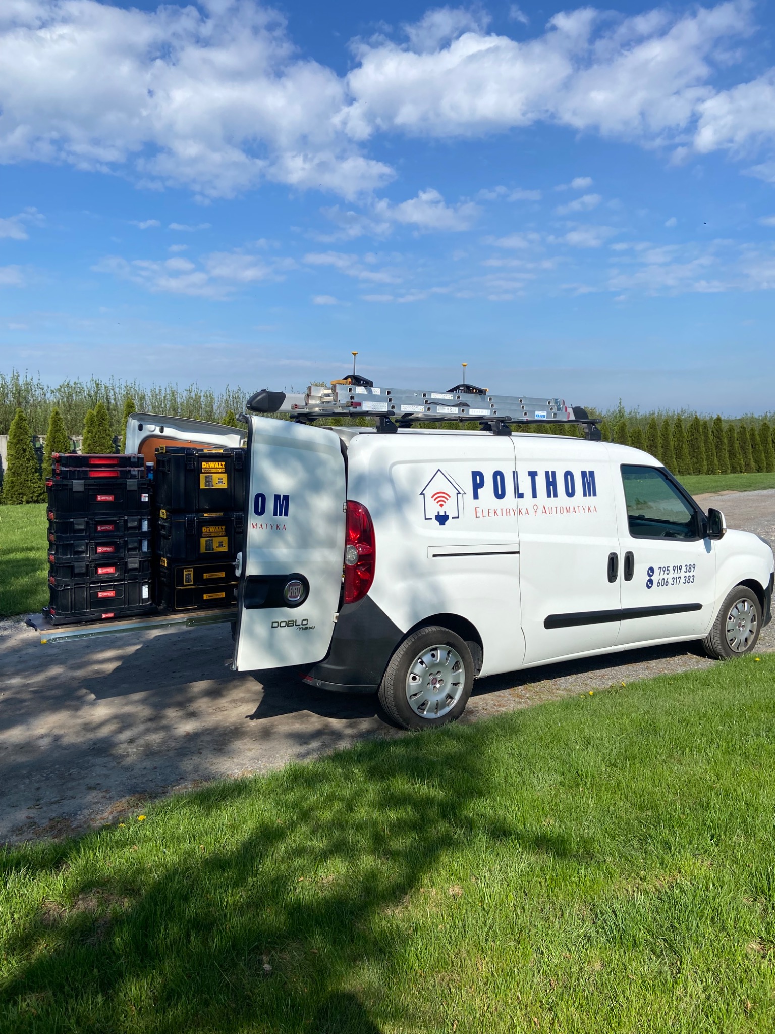 Biały samochód dostawczy z logo firmy Polthom Elektryka Automatyka, otwarty bagażnik z wysuwanymi skrzynkami narzędziowymi DeWalt i Oprix, drabina na dachu.