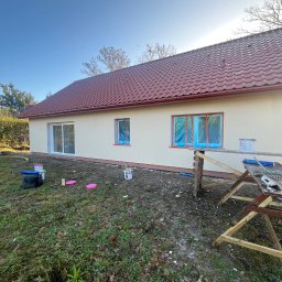 Bohdan Onyshchuk - Dom jednorodzinny po tynkowaniu, z oknami zabezpieczonymi folią i rozstawionym rusztowaniem. Świeżo nałożony tynk w kolorze kremowym.