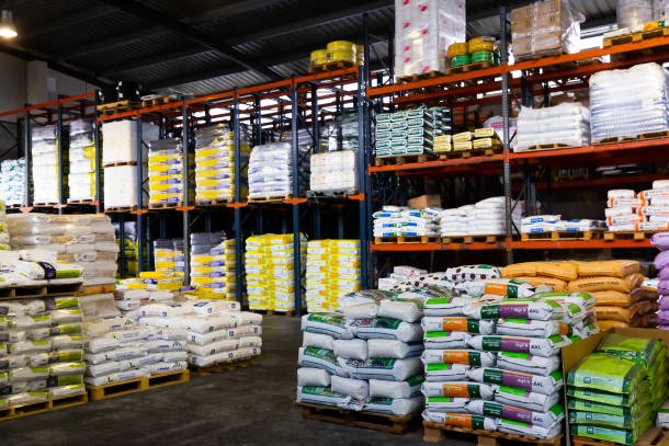 Magazyn z paletami worków na regałach. Różne kolory i rodzaje opakowań. Widok na pełne półki z zapasami. Oświetlenie magazynowe.