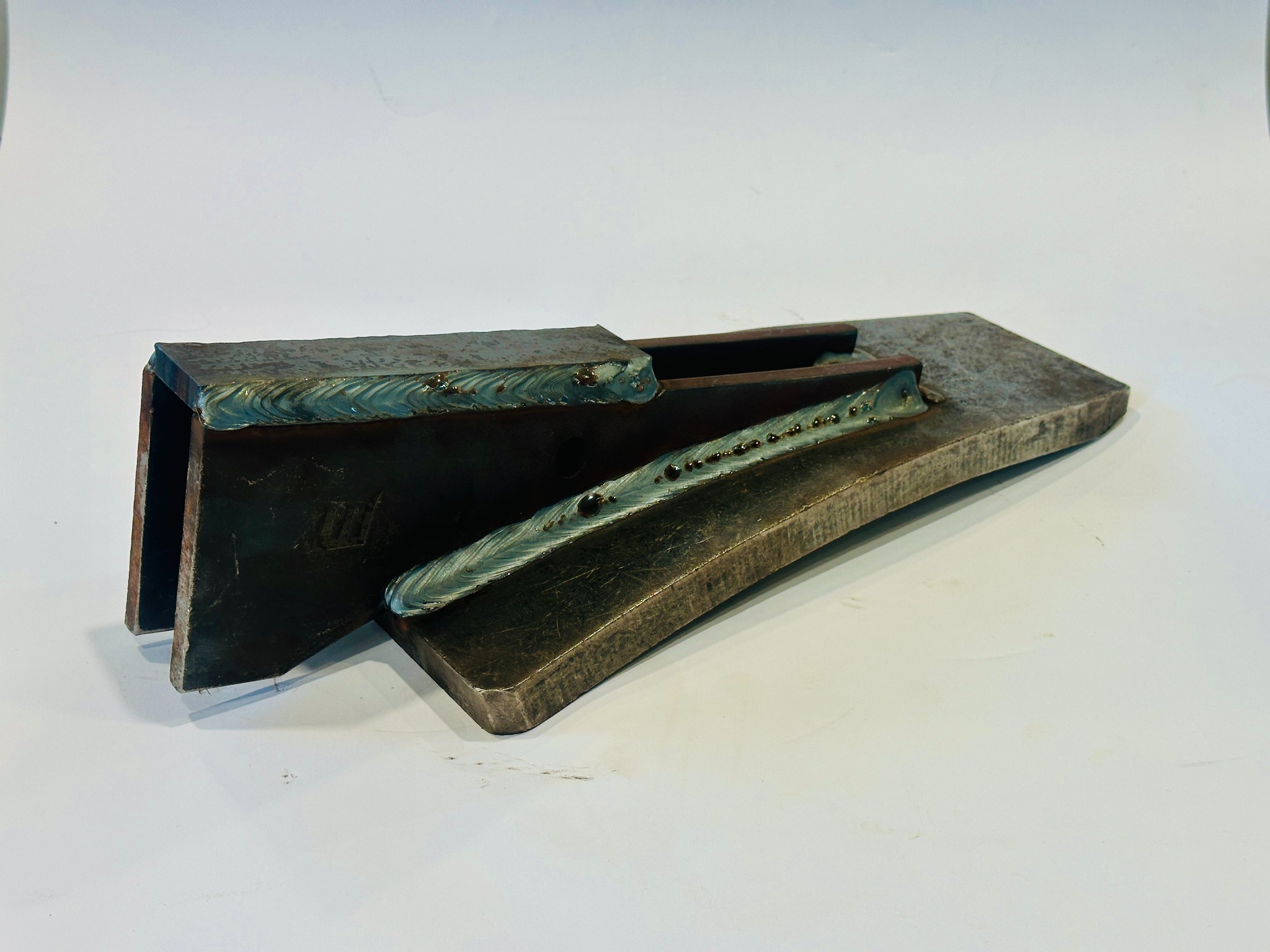 Metalowe elementy połączone spawem, widoczne ślady obróbki. Prezentacja umiejętności łączenia metali, detale spoin i struktura materiału.