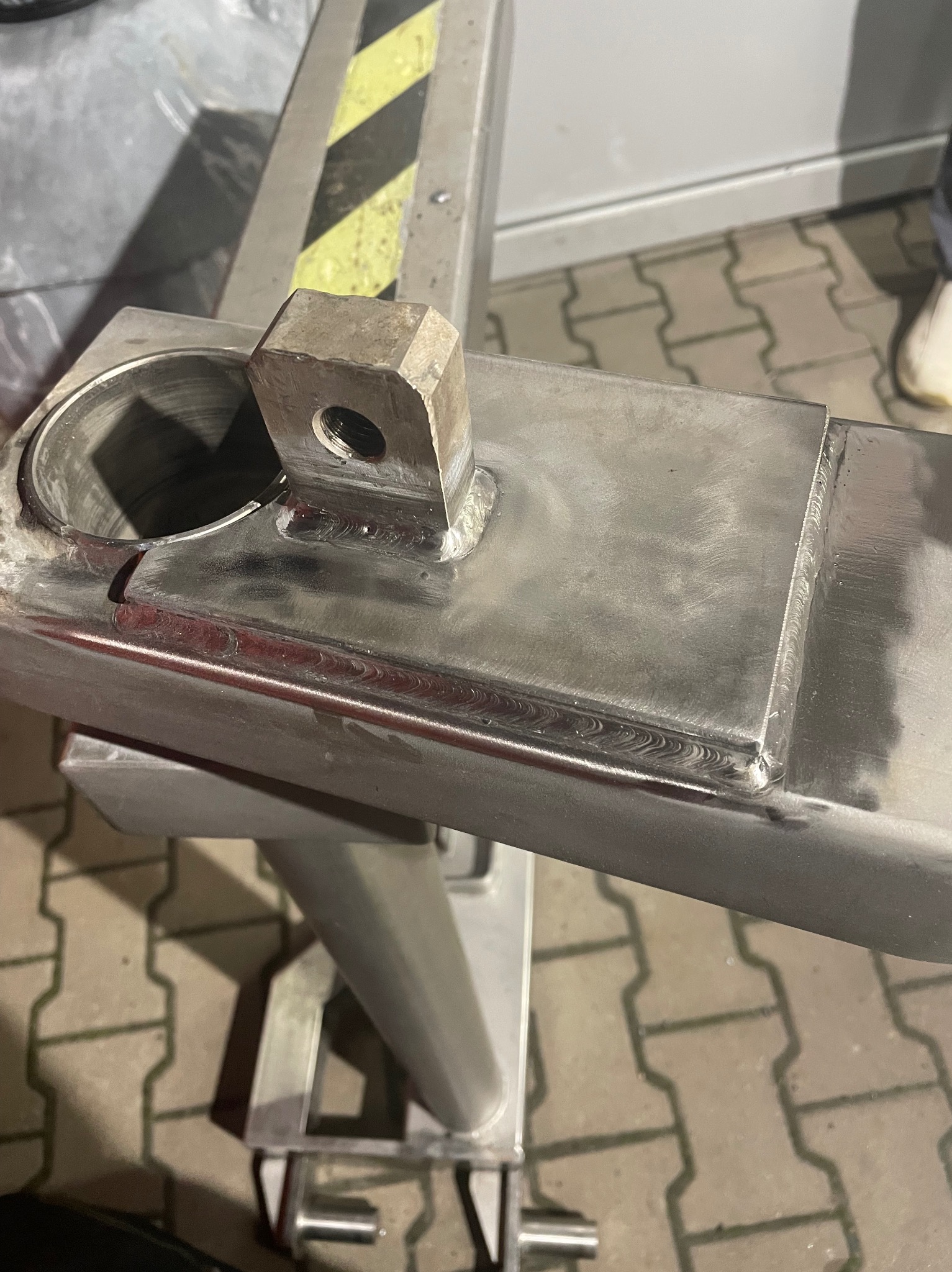 Detal spawu na metalowej konstrukcji z widocznymi śladami obróbki i żółto-czarnym oznaczeniem, ukazujący precyzję wykonania.