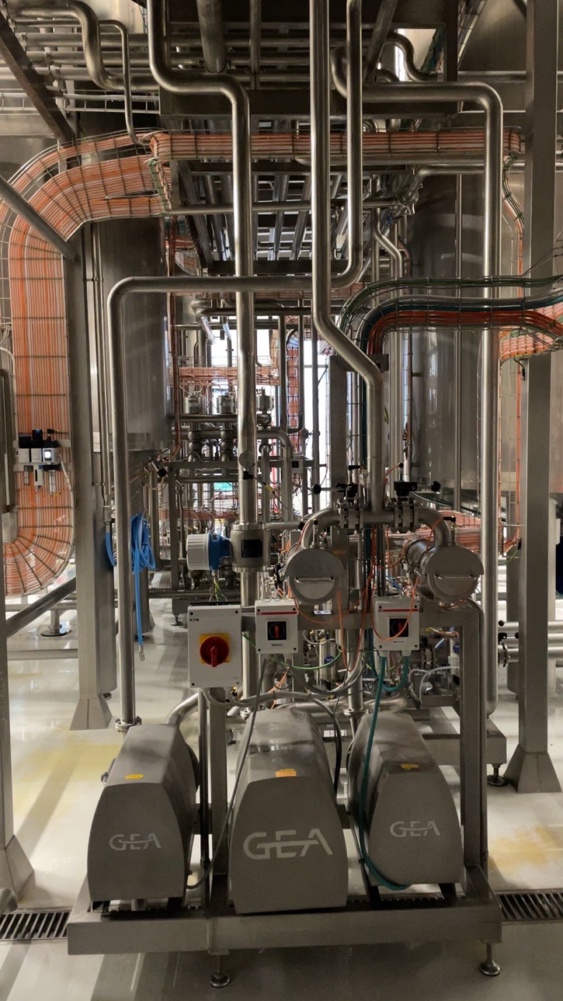Kompleksowa instalacja przemysłowa z rurami, przewodami i urządzeniami GEA. Widoczne liczne zawory, przełączniki i elementy sterujące. Precyzyjne wykonanie i dbałość o detale.