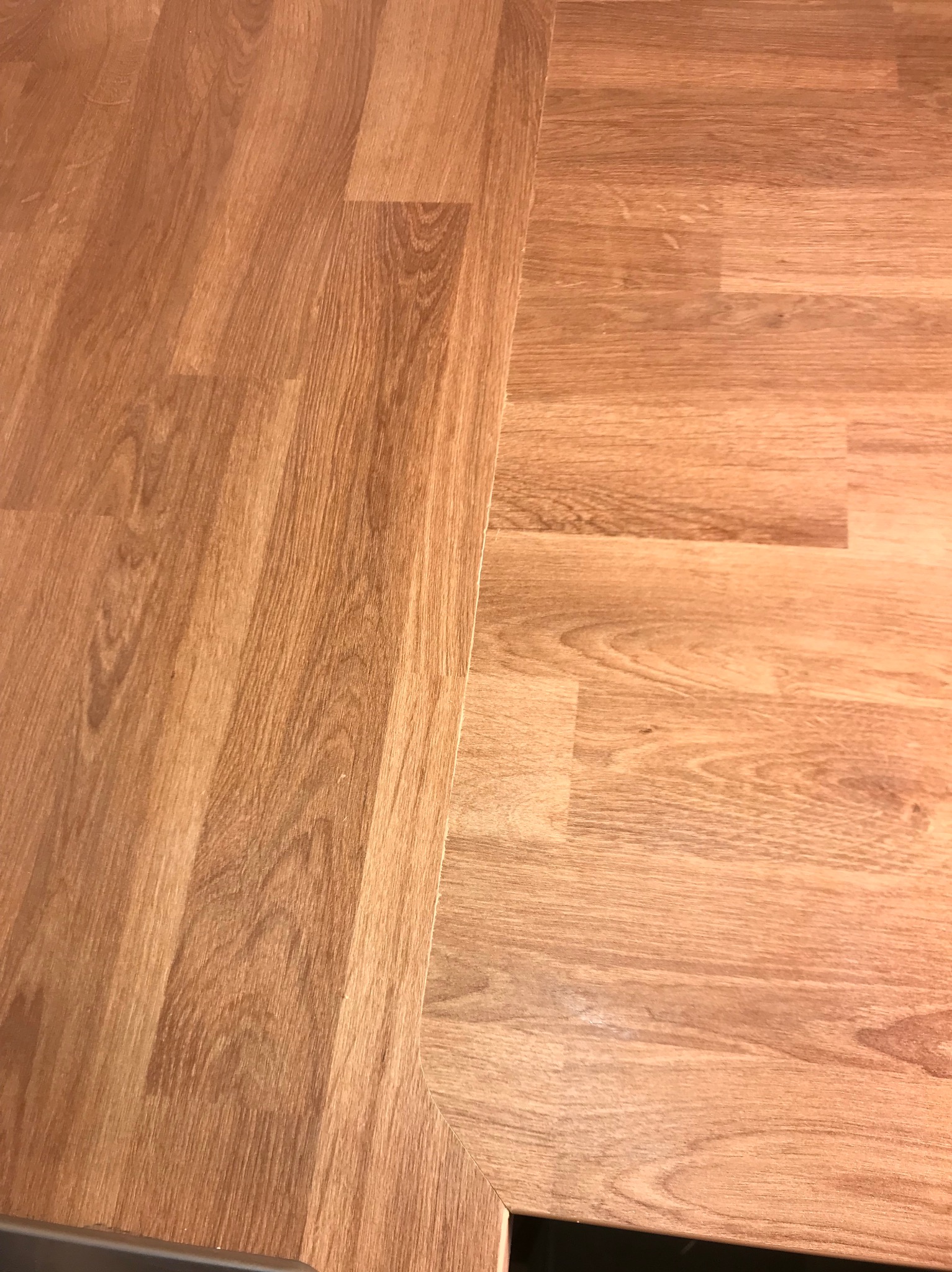 Ukończona podłoga z paneli imitujących drewno, ułożona w regularny wzór. Widoczny fragment przy listwie przypodłogowej i narożniku. Ciepła kolorystyka drewna.