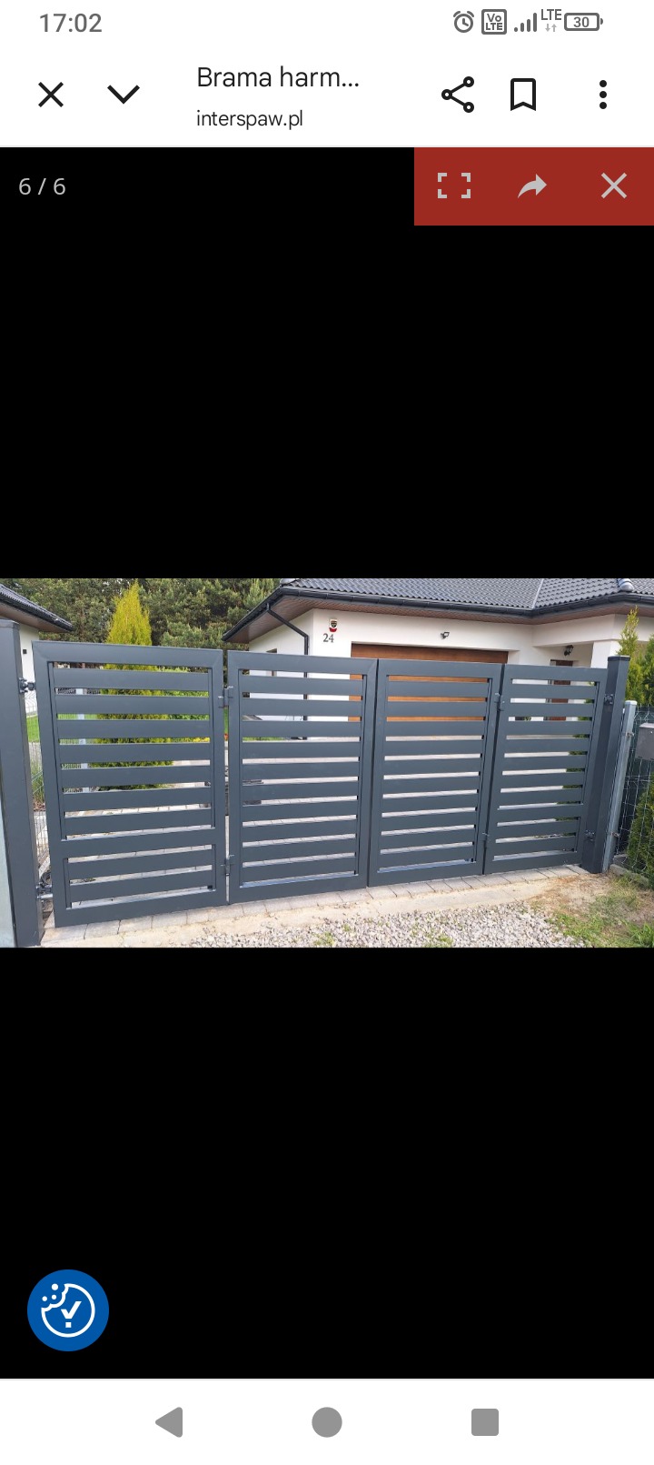 Nowoczesna, szara brama wjazdowa harmonijkowa z poziomymi panelami, zamontowana przed domem z numerem 24. Widoczne elementy mocujące i fragment ogrodzenia.