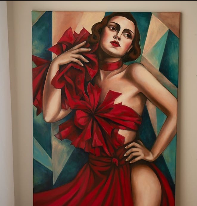 Obraz olejny przedstawiający kobietę w czerwonej sukni z kokardami na tle geometrycznym w odcieniach błękitu i beżu. Widoczne pociągnięcia pędzla, stylizowane na art deco.