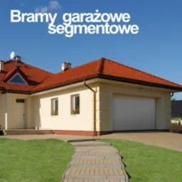 Nowoczesny garaż z kremową elewacją i czerwoną dachówką, z białą segmentową bramą garażową, widok z perspektywy ścieżki prowadzącej do garażu w słoneczny dzień.