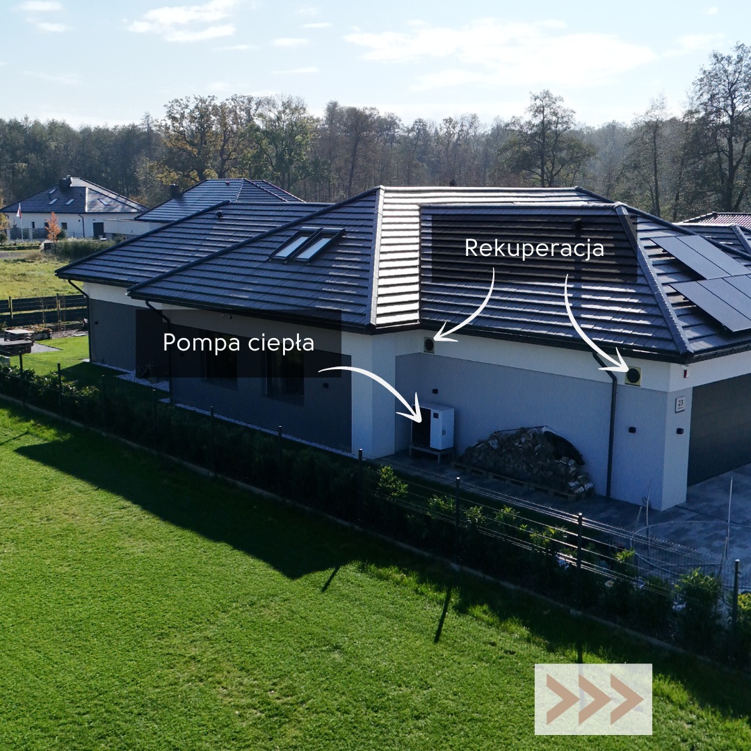 Dom jednorodzinny z pompą ciepła i systemem rekuperacji, widok z góry, zielony trawnik, nowoczesna architektura, panele słoneczne na dachu.