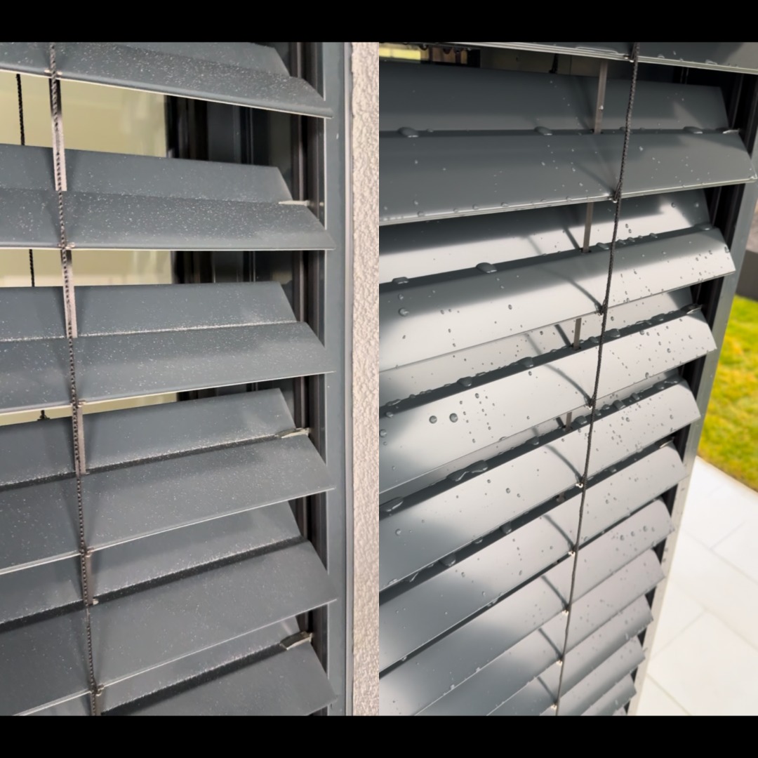 Szare, aluminiowe żaluzje zewnętrzne po deszczu, z widocznymi kroplami wody. Ujęcie z bliska, ukazujące detale konstrukcji i świeżość po czyszczeniu.
