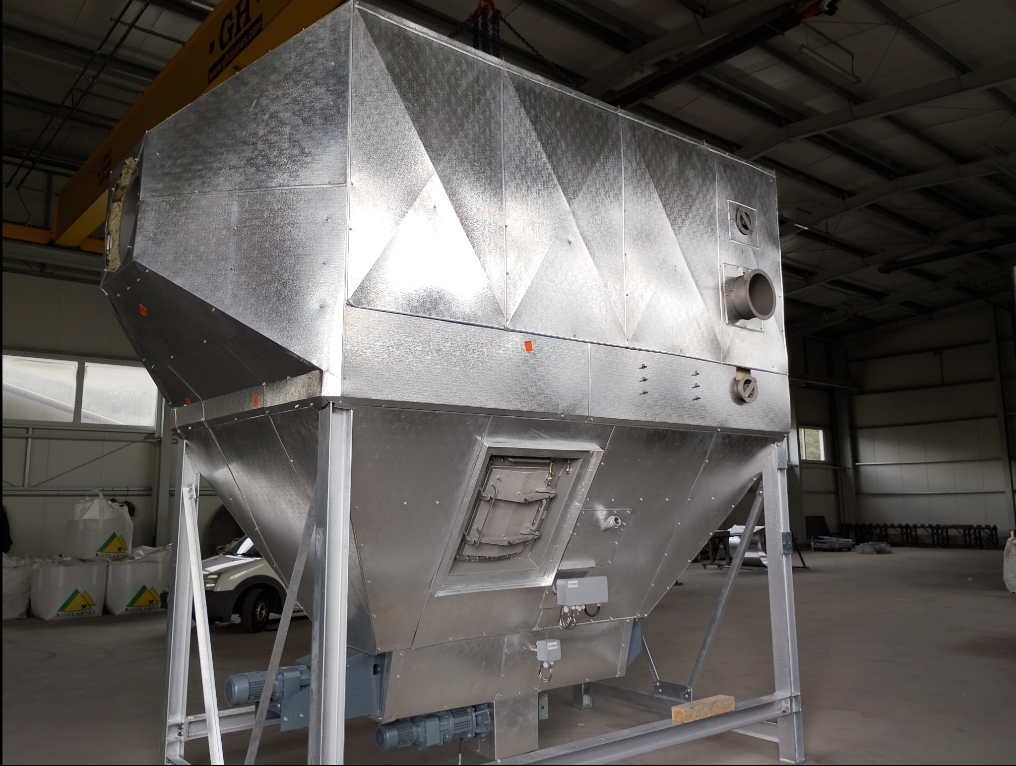 Metalowa konstrukcja przemysłowa z elementami blacharskimi, widoczne łączenia i otwory wentylacyjne, umieszczona w hali produkcyjnej. Detaliczna obróbka blachy.