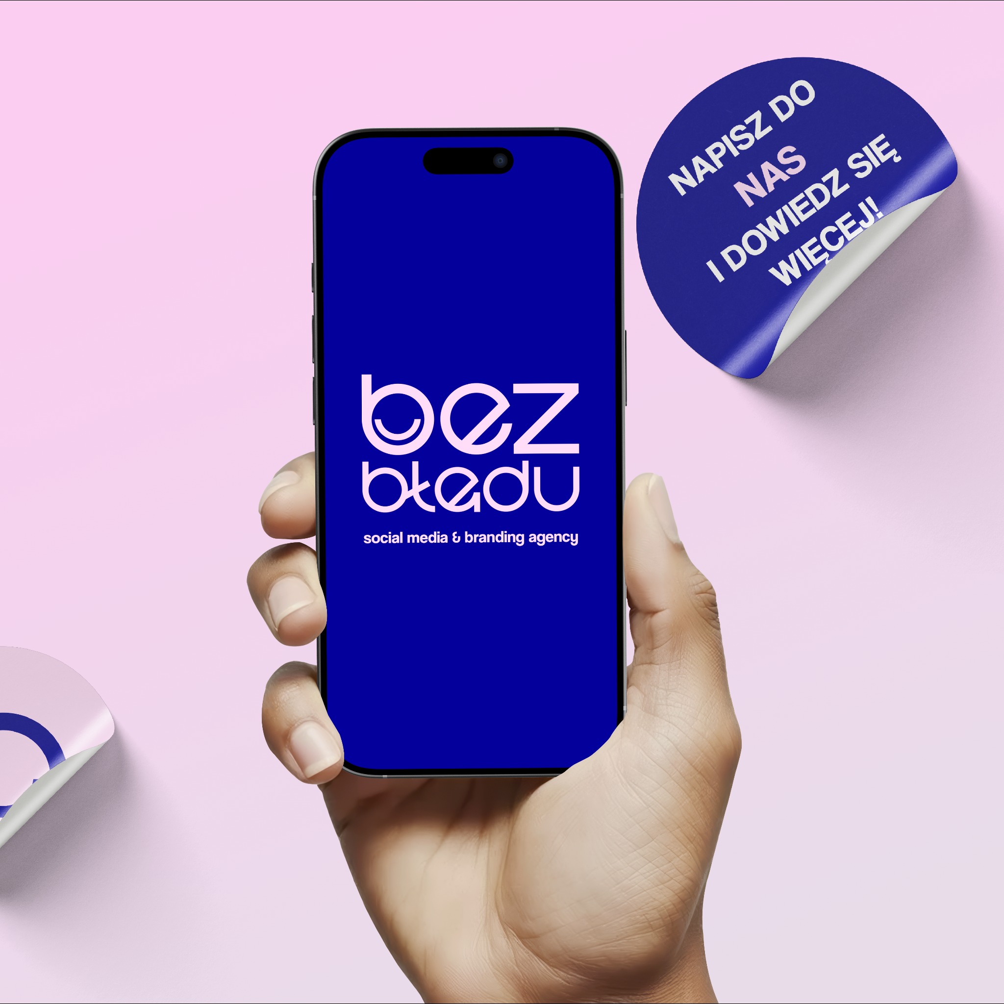 Dłoń trzyma smartfon z logo 'bez błędu' (social media & branding agency) na niebieskim ekranie. Obok naklejka z hasłem 'Napisz do nas i dowiedz się więcej!'.