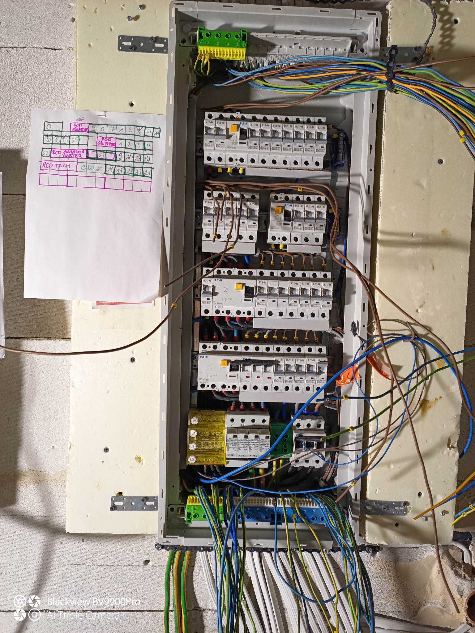 Rozdzielnica elektryczna z zabezpieczeniami i okablowaniem w Biskupcu. Widoczna tabliczka z opisem obwodów. Instalacja w trakcie prac, widoczne kable.