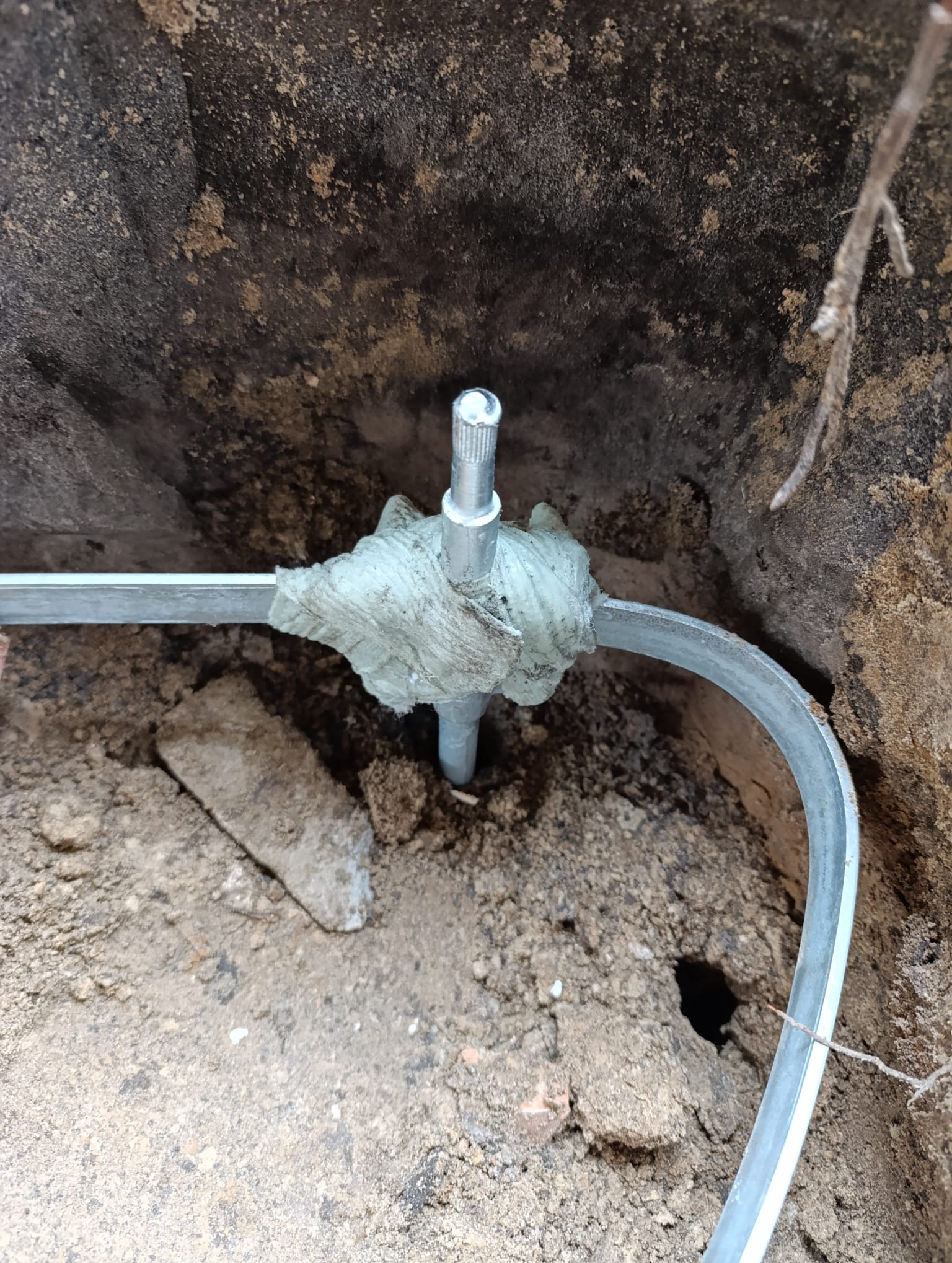 Uziemienie pionowe z bednarką, zabezpieczone taśmą izolacyjną, w wykopie ziemnym. Element instalacji odgromowej.