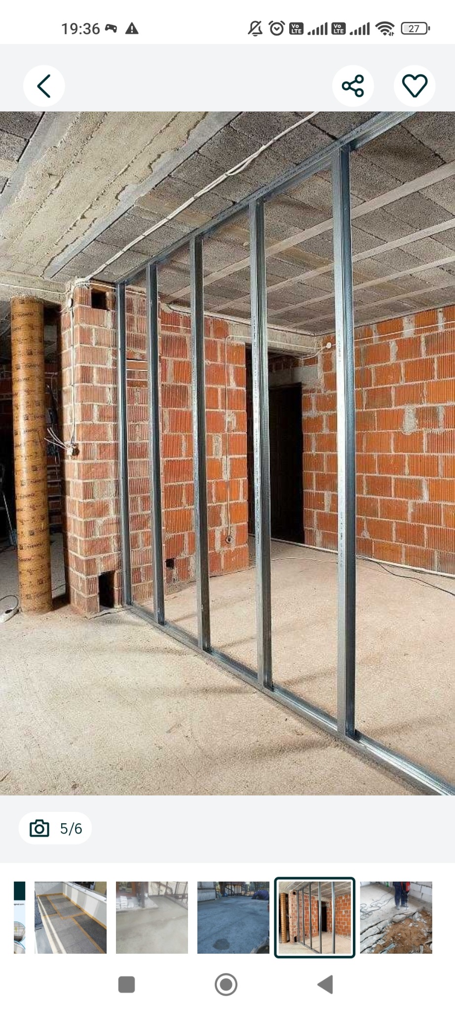 Montaż metalowej konstrukcji ścianki działowej na tle surowej cegły w remontowanym wnętrzu. Widoczne profile pionowe i poziome, surowy betonowy strop.