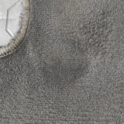 Szwagier Cleaner - Szczegółowe zbliżenie na szarą, teksturowaną powierzchnię dywanu z fragmentem metalowego elementu w lewym górnym rogu. Widoczne delikatne cieniowanie i struktura włókien.