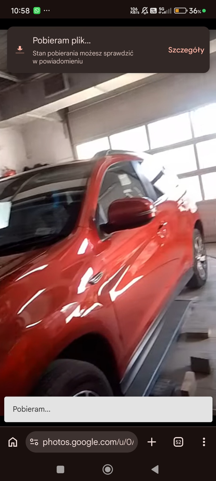 Czerwony SUV na podnośniku w warsztacie. Widoczne odbicia światła na karoserii, podkreślające świeżość lakieru. Auto po blacharce/lakierowaniu, gotowe do odbioru.