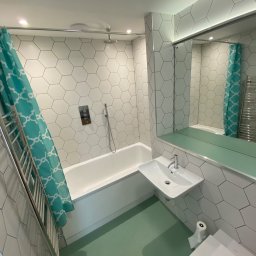 DANIEL DURDA DAN-BUD USŁUGI WYKOŃCZENIOWE - Nowoczesna łazienka z heksagonalnymi płytkami, turkusową zasłoną prysznicową i podłogą w odcieniu mięty. Minimalistyczna umywalka i grzejnik drabinkowy.