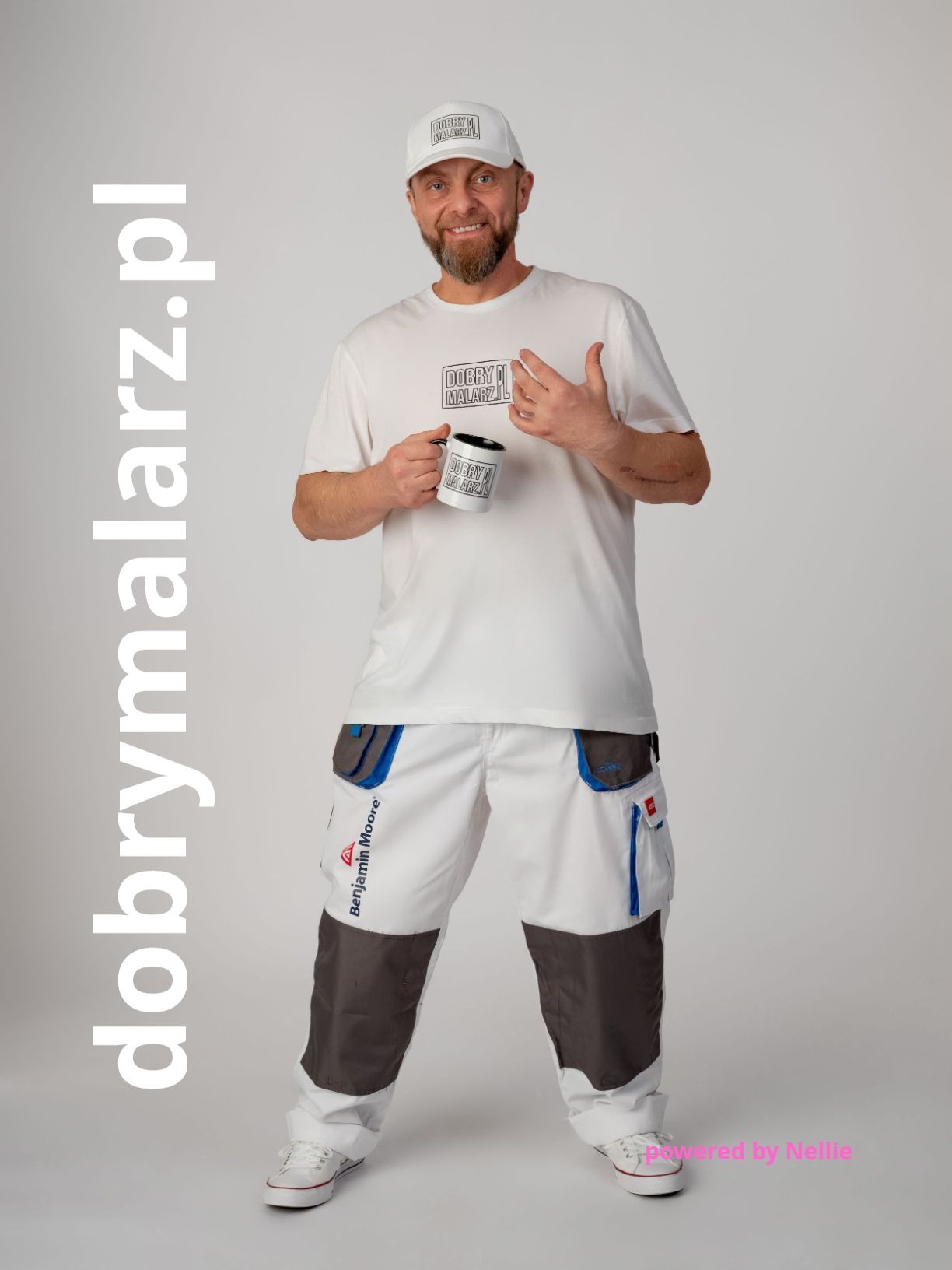 Uśmiechnięty malarz w firmowej odzieży, trzymający kubek z logo firmy na jasnym tle. Widoczne spodnie robocze z logo Benjamin Moore.