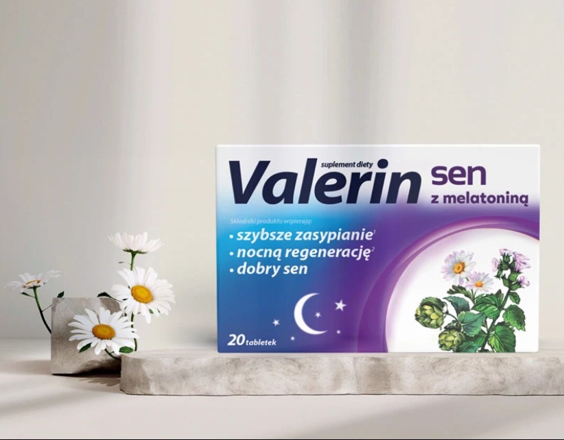 Opakowanie suplementu diety Valerin Sen z melatoniną, umieszczone na kamiennym postumencie, obok wazonika z białymi stokrotkami. Produkt na sen i regenerację.