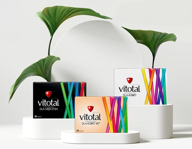 Elegancka prezentacja trzech opakowań suplementu Vitotal (dla mężczyzn, kobiet 40+, kobiet) na białych postumentach, z zielonymi liśćmi w tle i minimalistycznym, okrągłym elementem.