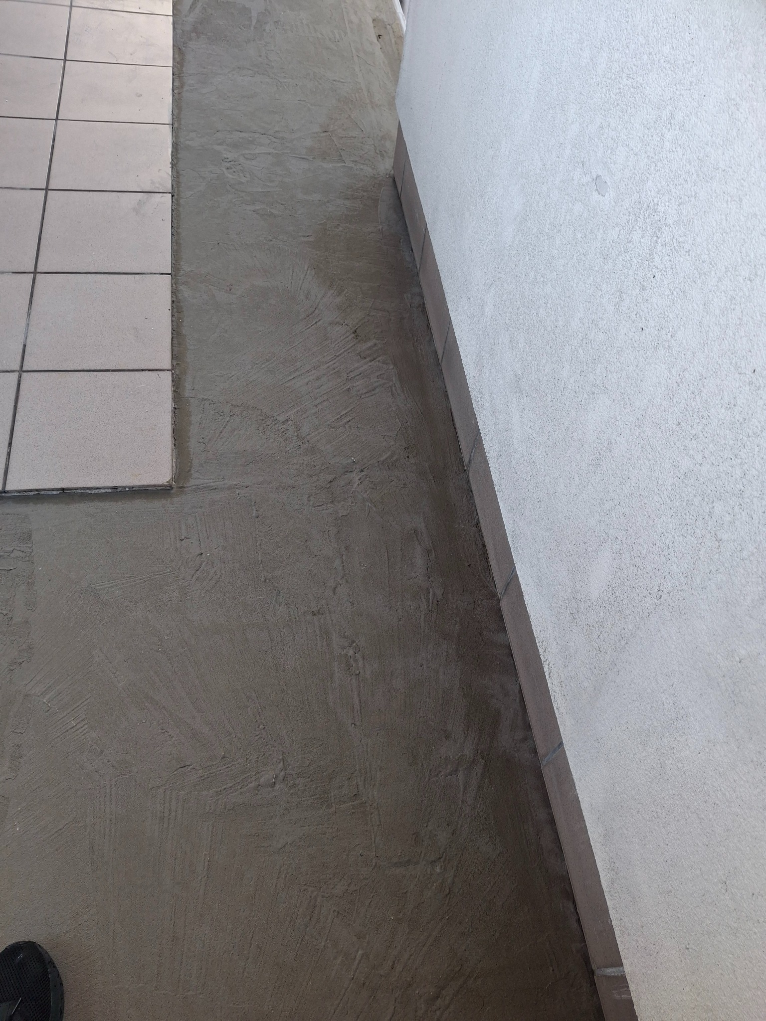 Przygotowanie podłoża pod płytki na balkonie w Nowym Modlinie. Wyrównana wylewka sąsiaduje z fragmentem ułożonej już podłogi z płytek.