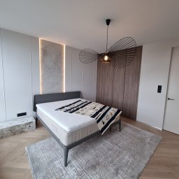 COMFORTbud KOSTIANTYN OVCHINNIKOV - Nowoczesna sypialnia z łóżkiem, designerską lampą i drewnianą podłogą w jodełkę. Minimalistyczny wystrój z akcentami marmuru i subtelnym oświetleniem.