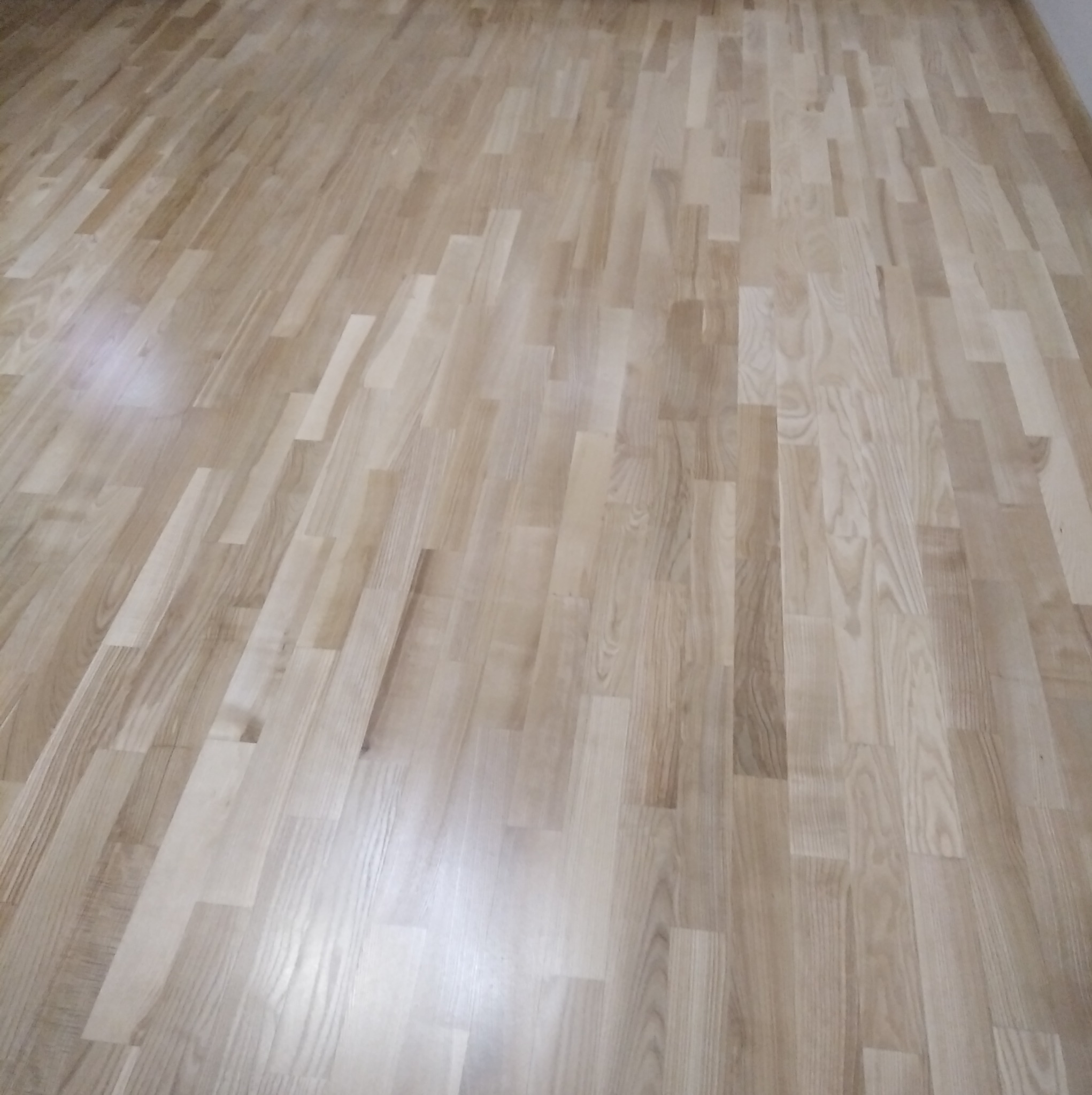 Jasny, dębowy parkiet ułożony w jodełkę francuską, widok z góry, ukazujący naturalny rysunek drewna i subtelne różnice w odcieniach poszczególnych klepek.