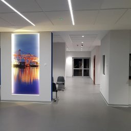 EL-SERWIS - Nowoczesne oświetlenie LED w korytarzu biurowym w Gdyni. Podwieszany sufit z liniowymi lampami, na ścianie podświetlona grafika z motywem portowym.