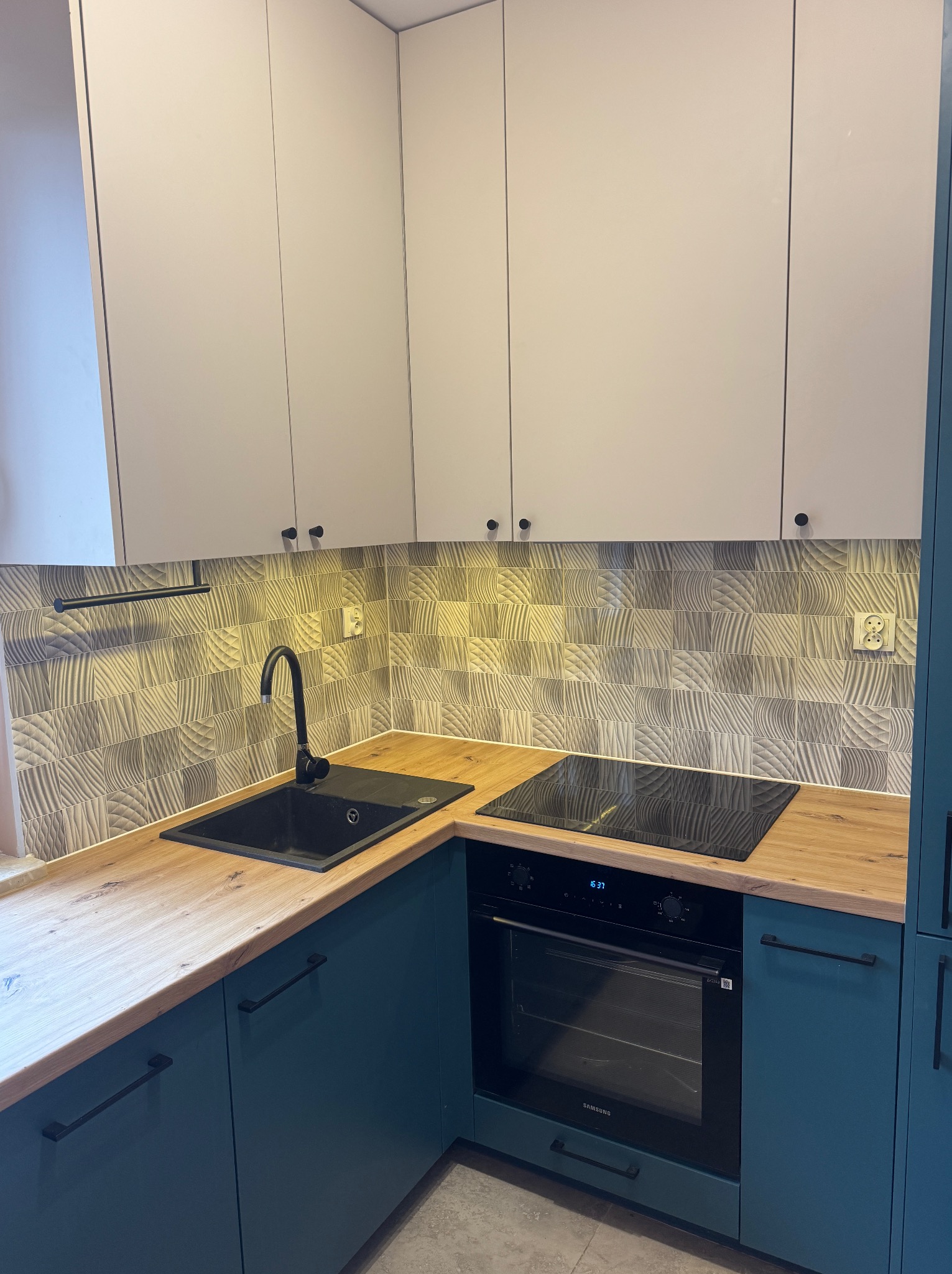 Nowoczesna kuchnia w Krakowie: turkusowe szafki dolne, jasne górne, drewniany blat i wzorzyste płytki. Czarny zlew i płyta indukcyjna. Stylowe wykończenie.